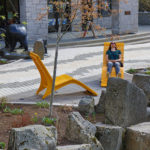 Women sitting on Yellow Chaise Lounge by rocks