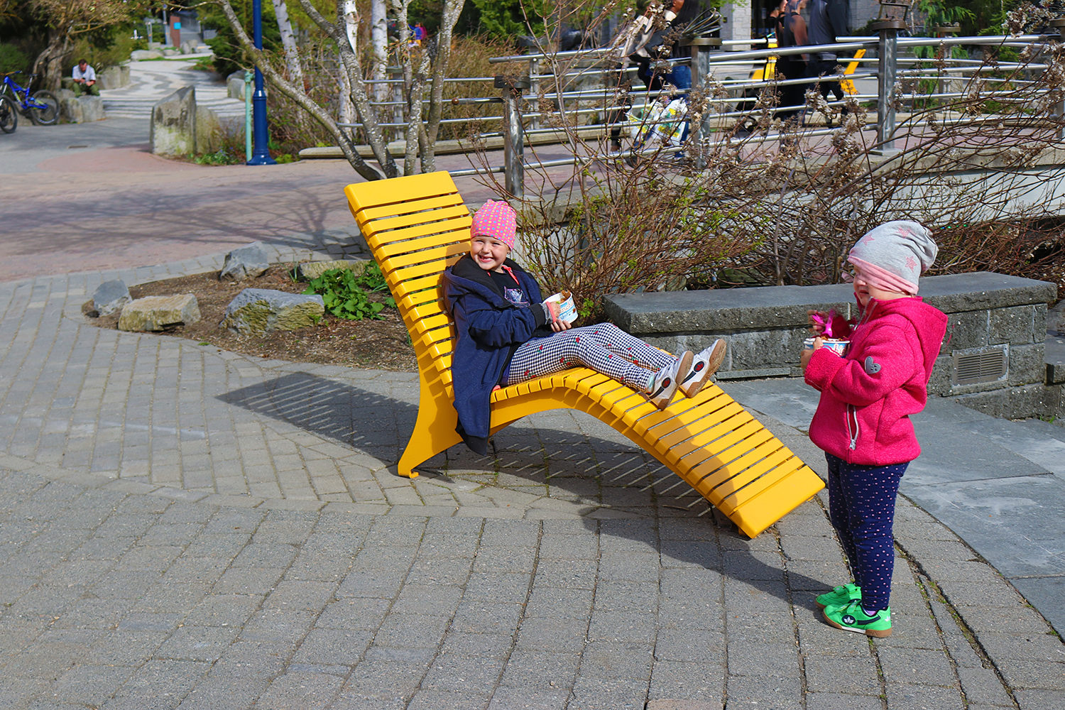 Little girl eating ice cream sitting on yellow chaise lounge