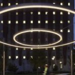 Circle of light suspended in sky with building behind