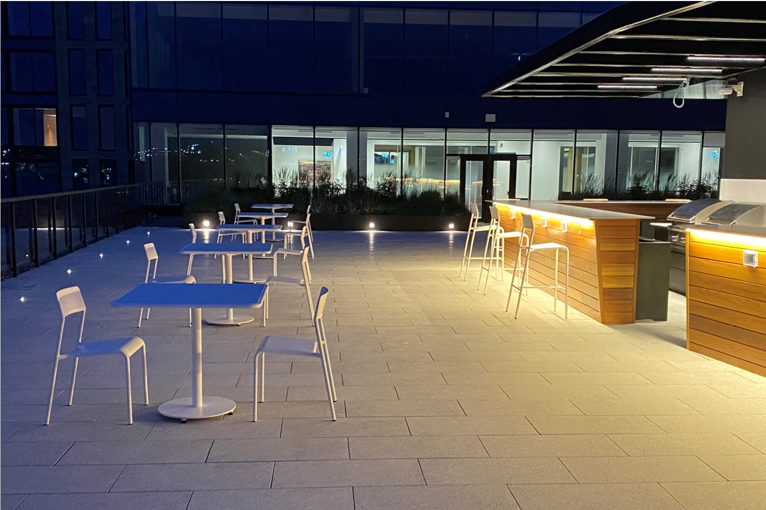 Night shot of Foro tables and chairs on roof top patio