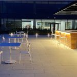 Night shot of Foro tables and chairs on roof top patio