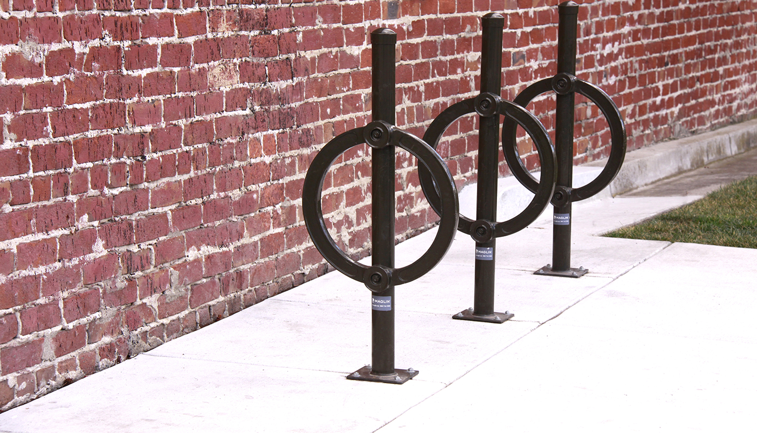 Black bike racks against a brick wall