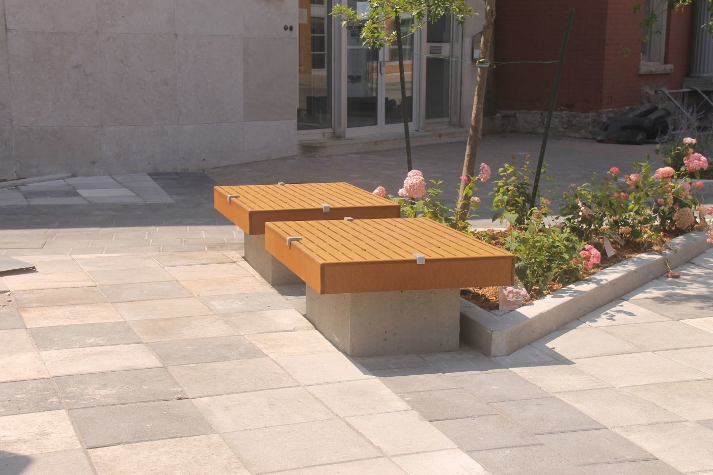 Two identical seating platforms near small flowerbed