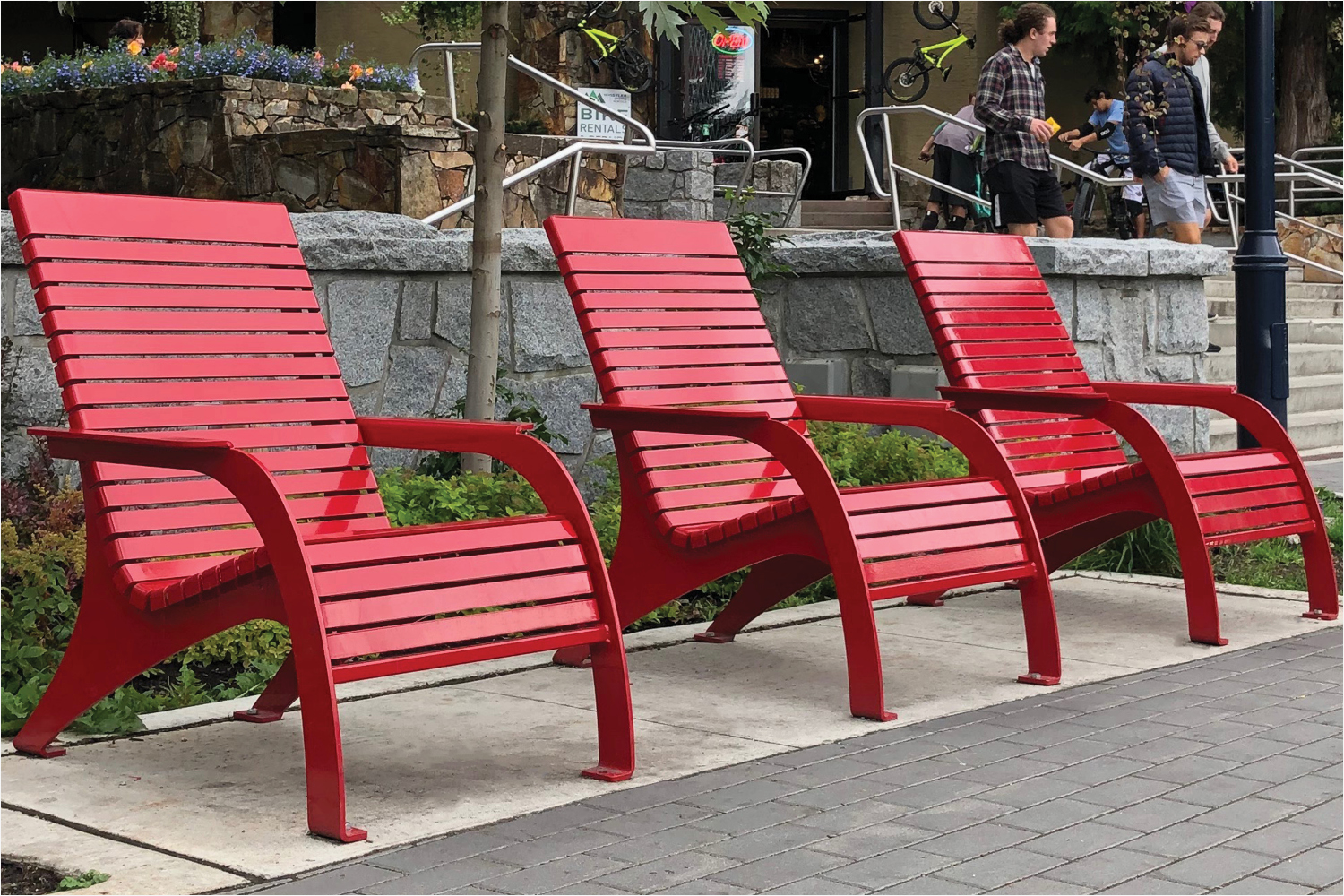Three red 720 Chairs with people in the background