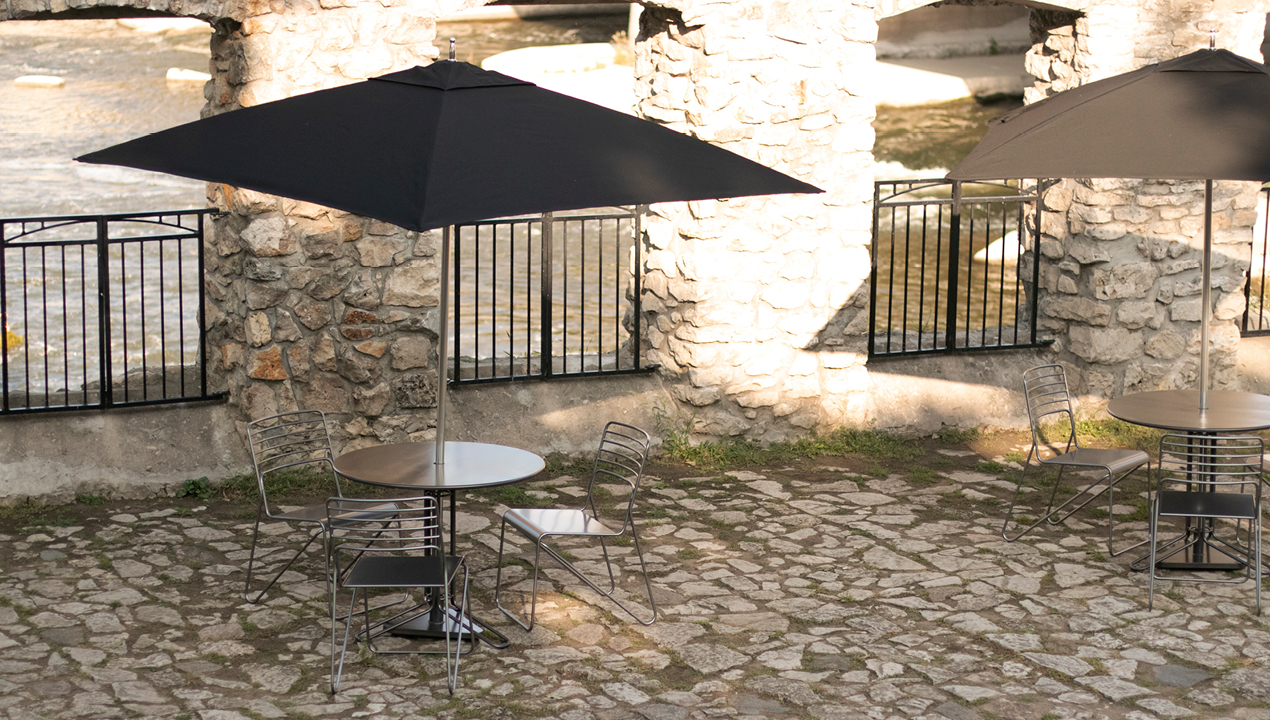 Three Metal Chairs with Round Table with an Attached Black Umbrella