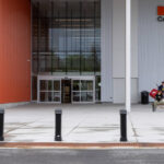 A person with hockey equipment walks toward the entrance of the Miskin Law Community Complex, home of Canadian Hockey Enterprises, drawing inspiration from its renowned installations and sporting legacy.