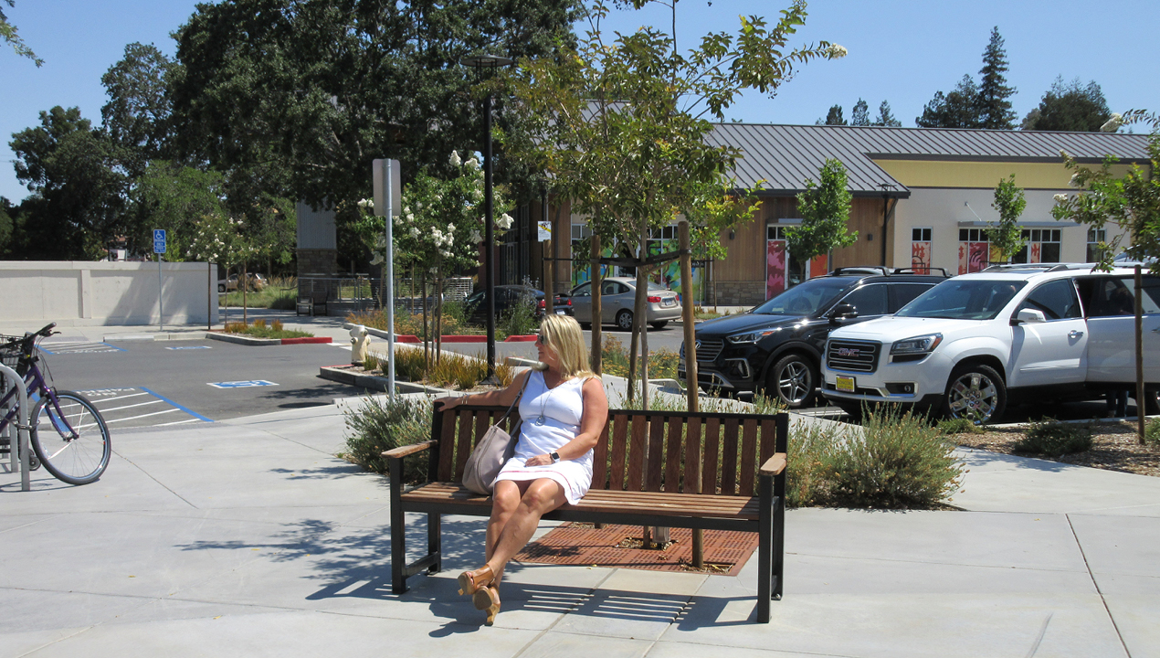 Woman in white sitting on backed bench