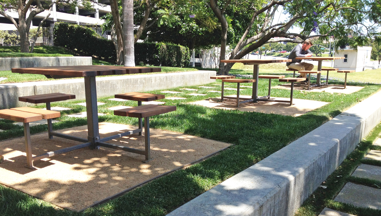 Three wooden tables with individual seatings outside on greens area
