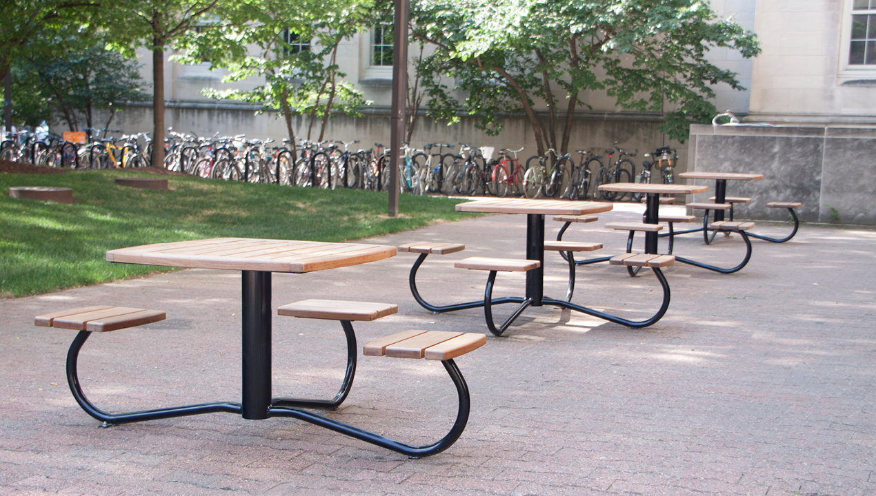 Multiple Tables with Individual Backless Seats outside near a Bike Rack