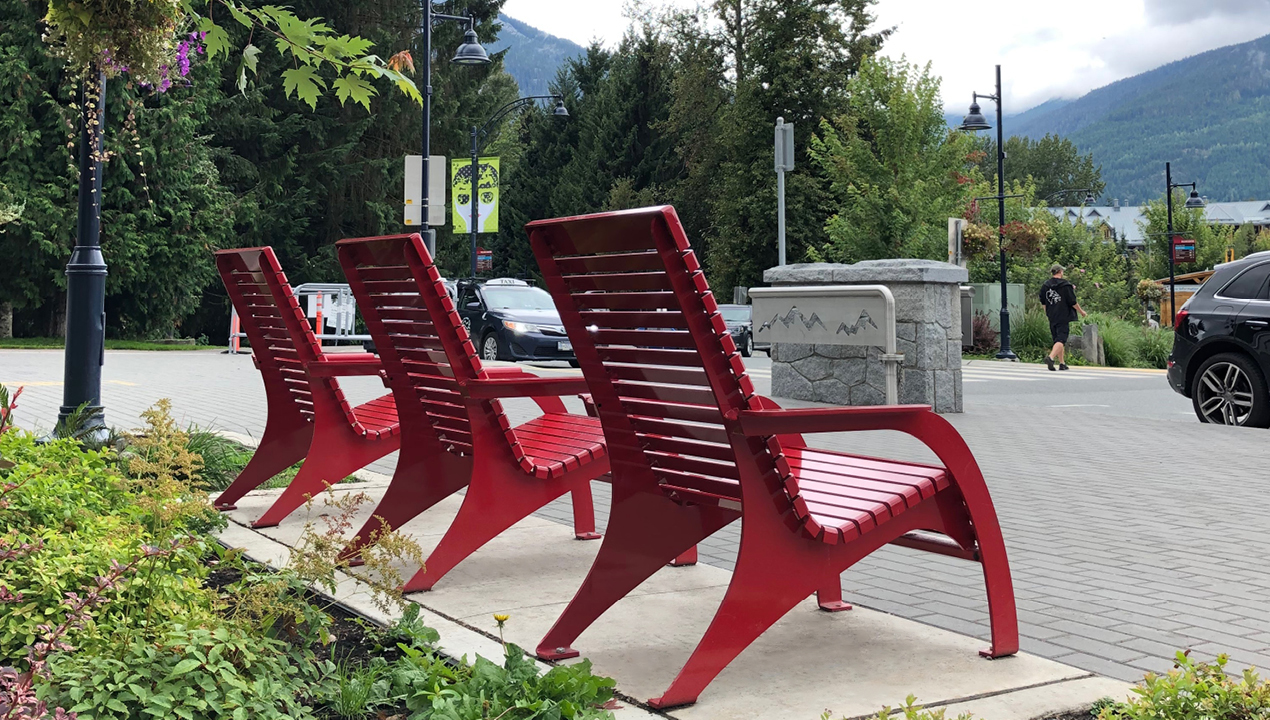 Three red 720 lounge chairs facing the mountains in Whistler