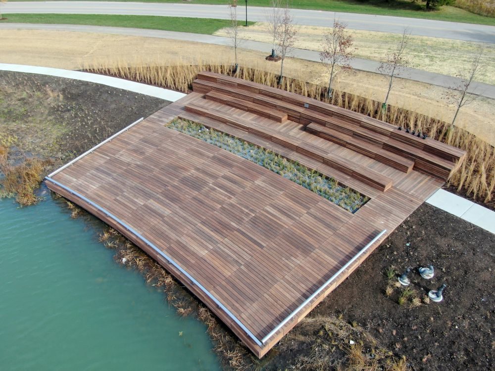 Custom Amphitheater, wooden stage next to water and greenery