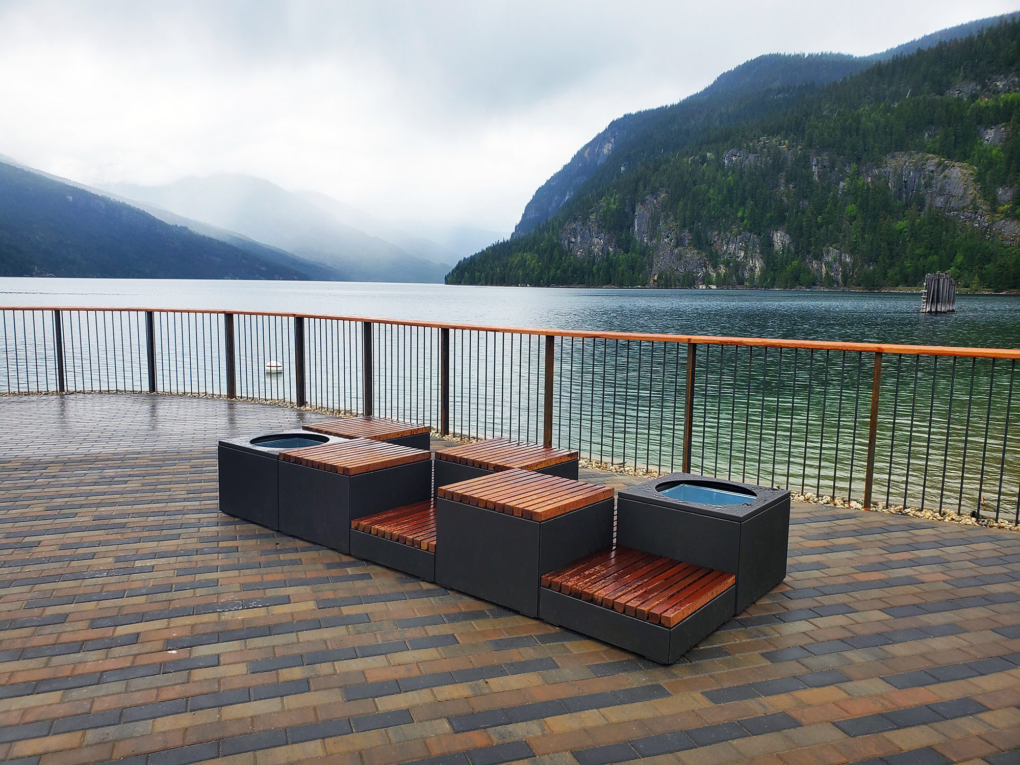 Bronze Pixel blocks with wood seats overlook a lake and mountains