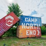Three stacked shipping containers are painted to read CAMP NORTH END