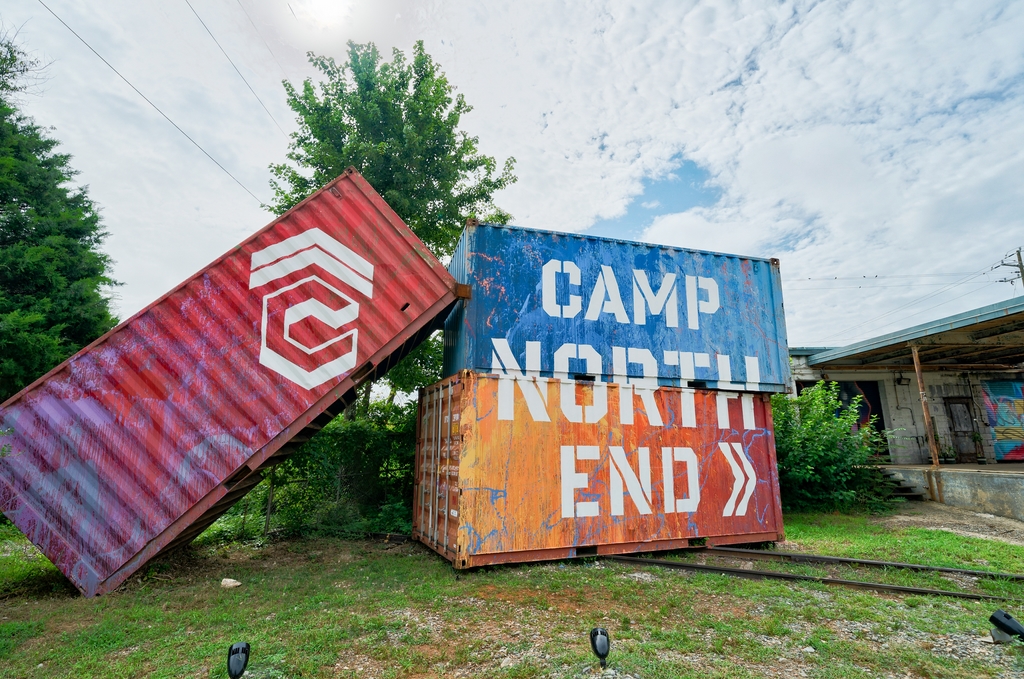 Camp-North-End-Shipping-Containers Three stacked shipping containers are painted to read CAMP NORTH END