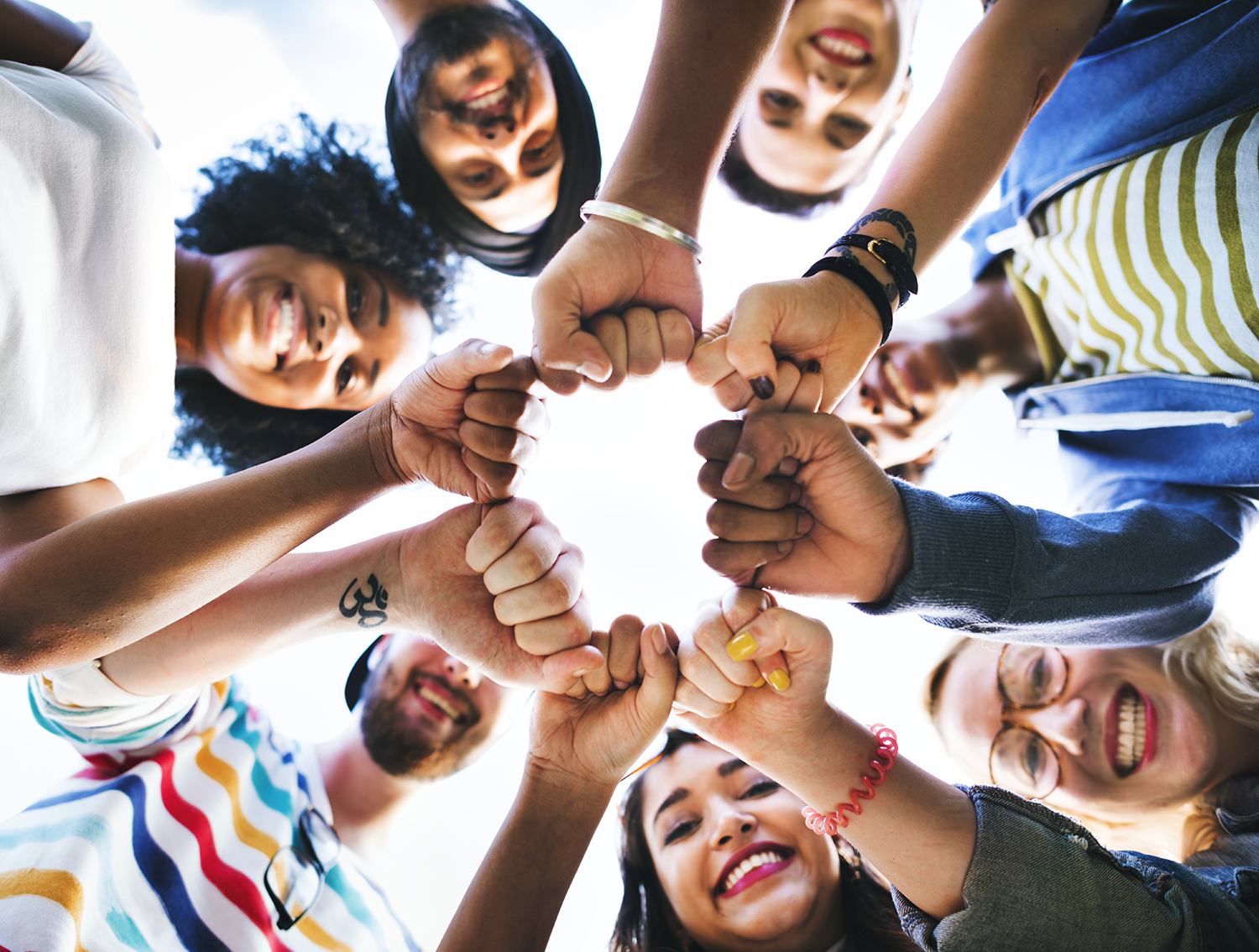 People in a circle with their fists out showing diversity