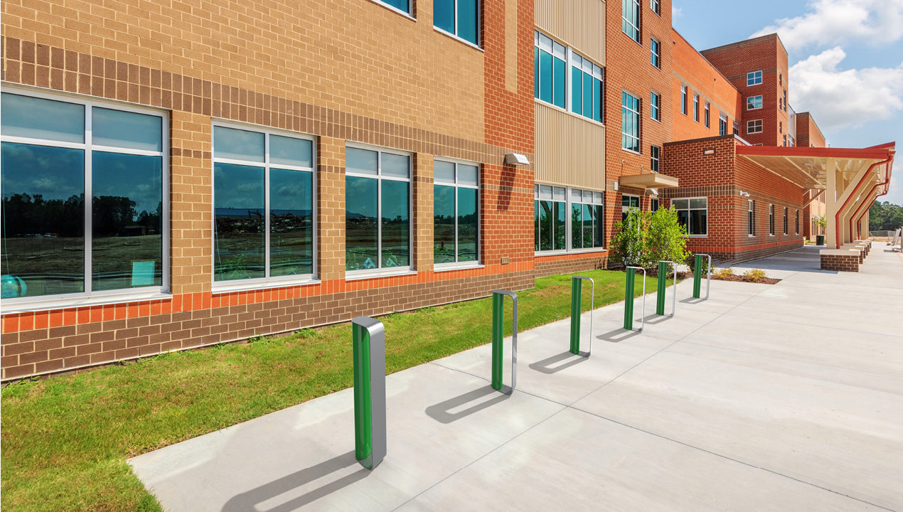 mbr-2900-00001_bike-racks MUG Bike Racks painted gloss green and gunmetal in front of school building