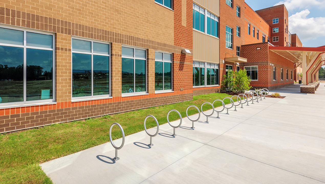 100 Series - 150 Bike Rack lined up in front of school building on bright day