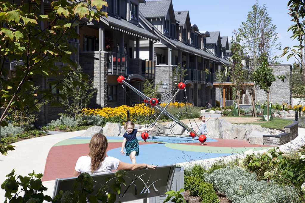 BC_Northgate Courtyard Playground_970 Bench_MLB970-M_001 A child on the playground runs from a playground to her mother, waiting on a park bench.