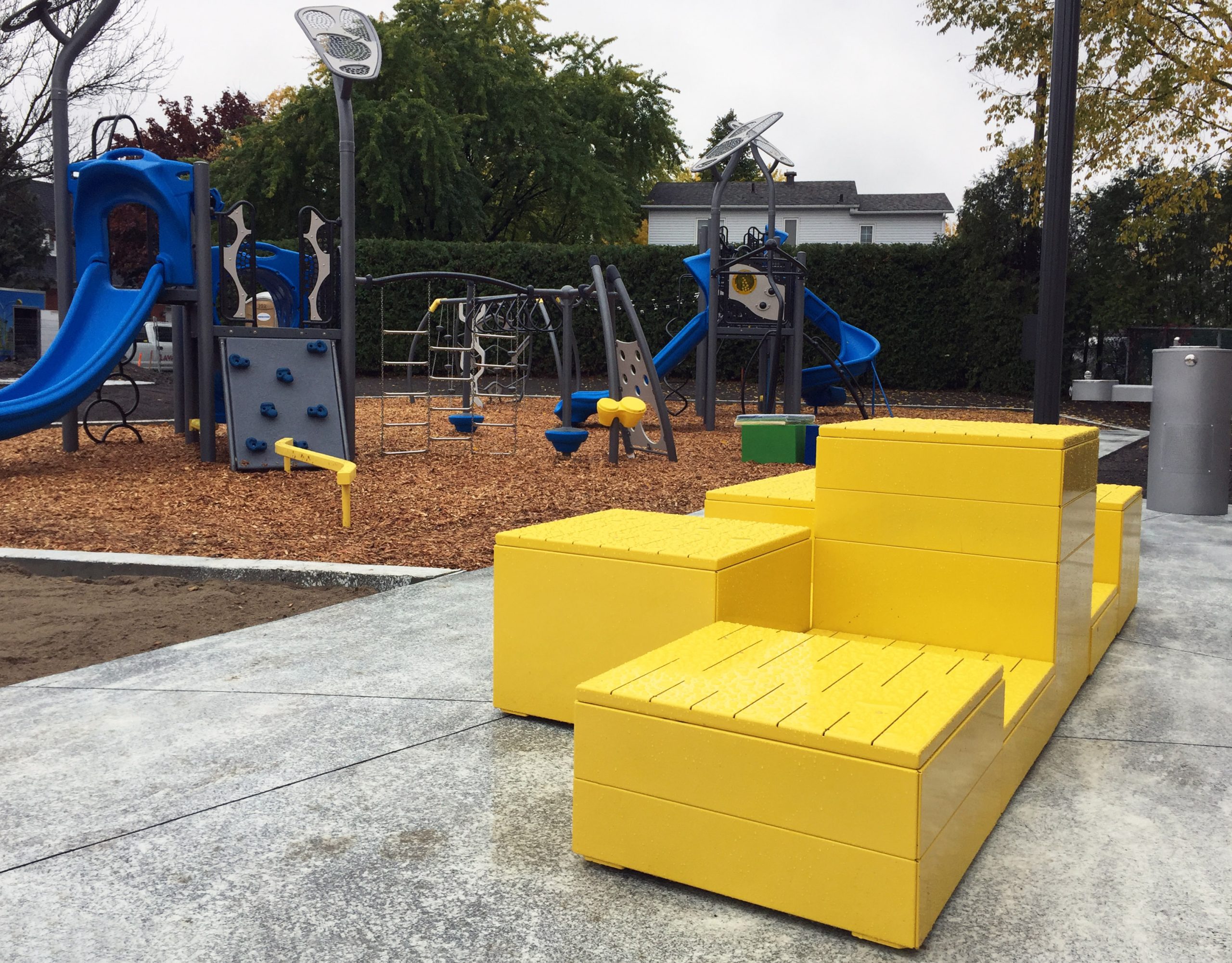 QC_Parc des Timoniers_Pixel_Yellow_Steel-Top_1 Yellow stacked Pixel layout with steel tops in foreground, playground structure in the background