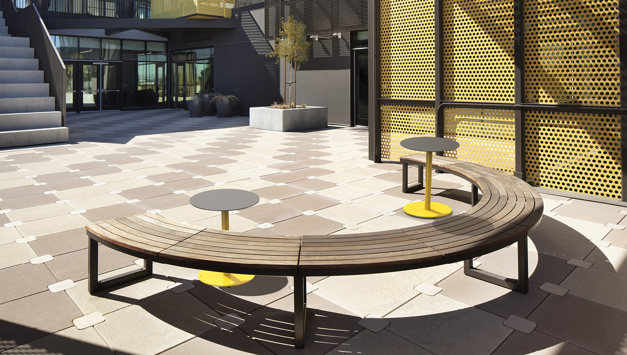 Curved Ogden Bench with two steel Ogden tables in courtyard