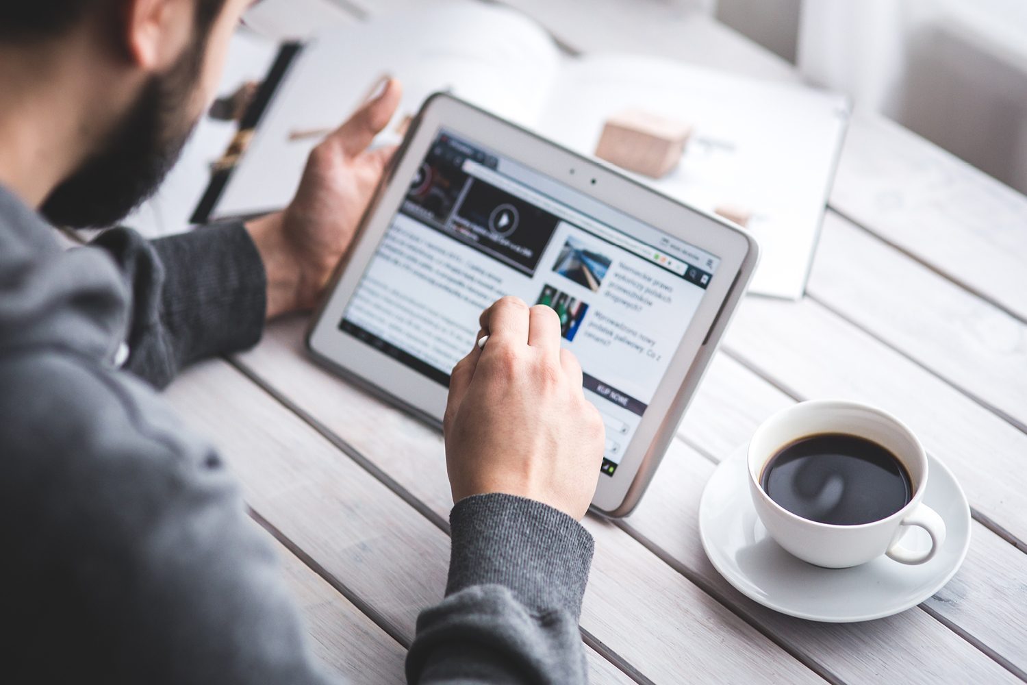 Guy reading Maglin product news on tablet with coffee