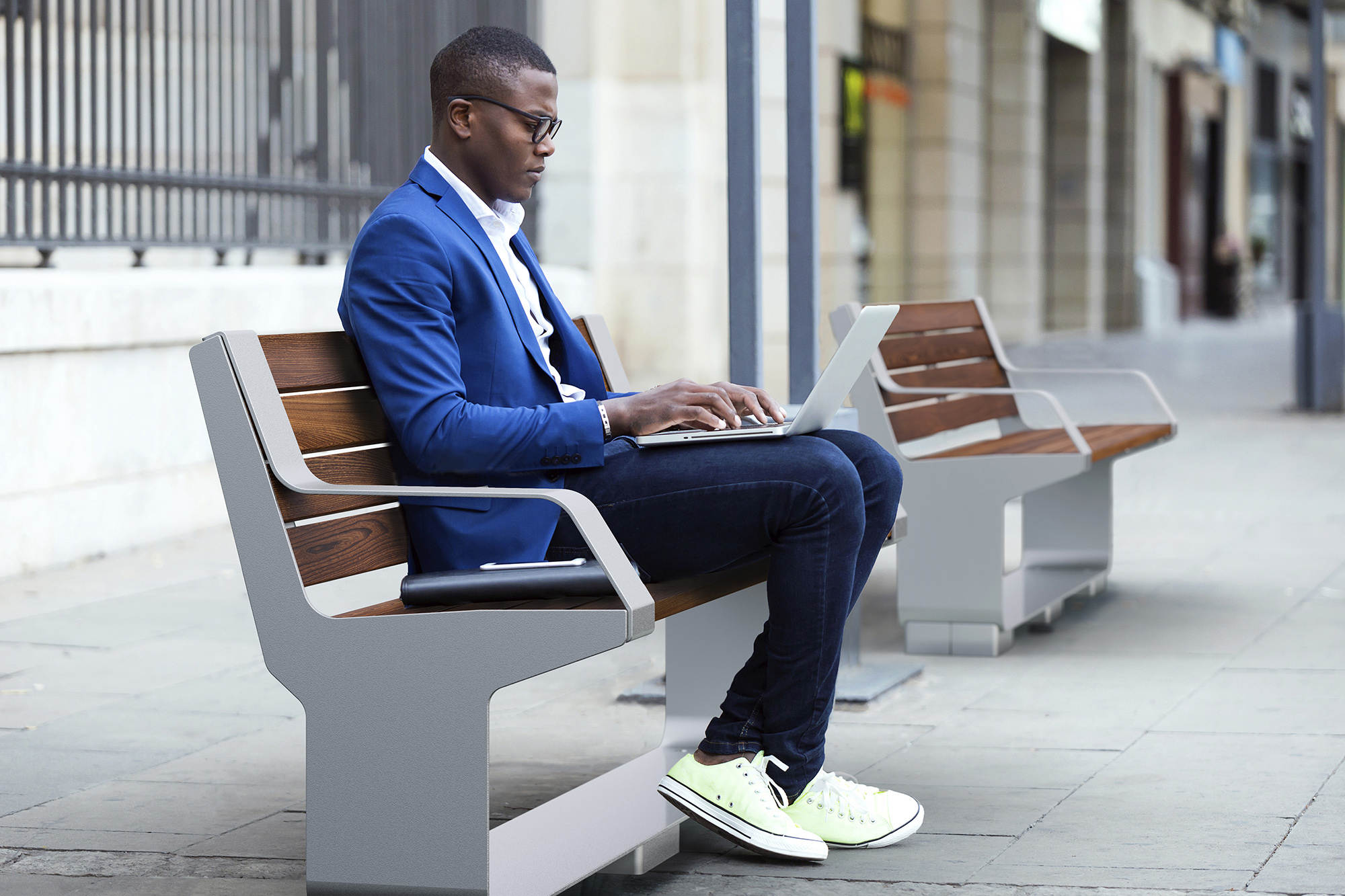 Man sitting on L-Series Backed Bench on city street
