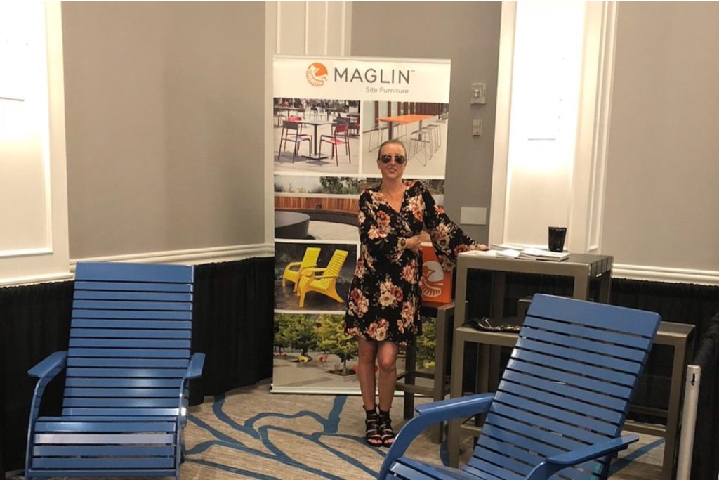 Jen-Fancy Jenn posing at a tradeshow next to some 720 chairs and a 1050 table