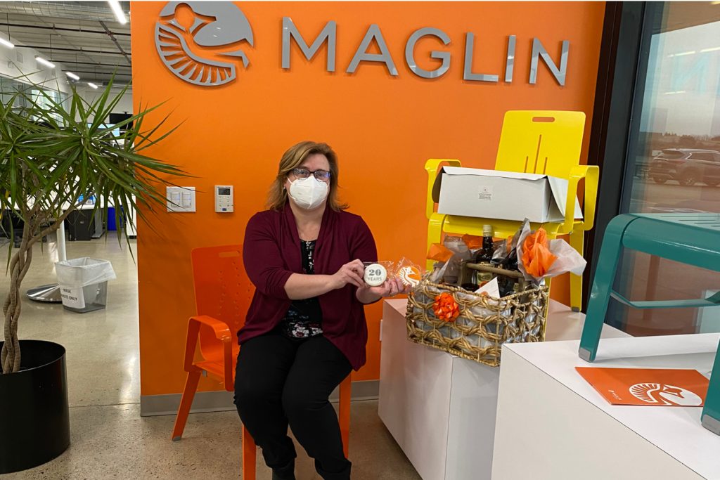 Linda-Atkinson Linda receiving her 20 years at Maglin gift against an orange wall