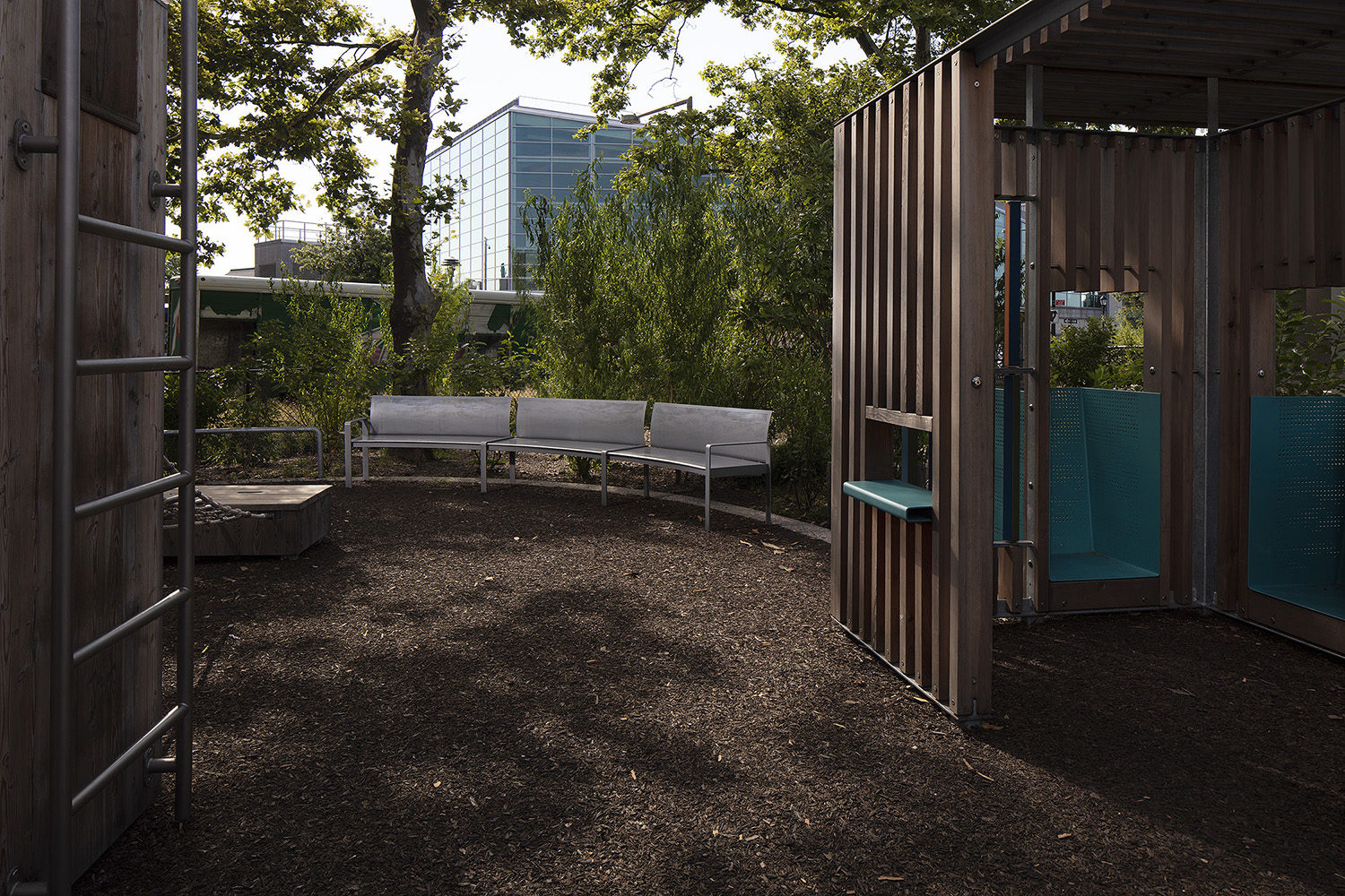 Curved custom Maglin benches behind a wooden play structure at the Battery Playscape