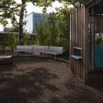 Curved custom Maglin benches behind a wooden play structure at the Battery Playscape