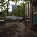 Curved custom Maglin benches behind a wooden play structure at the Battery Playscape