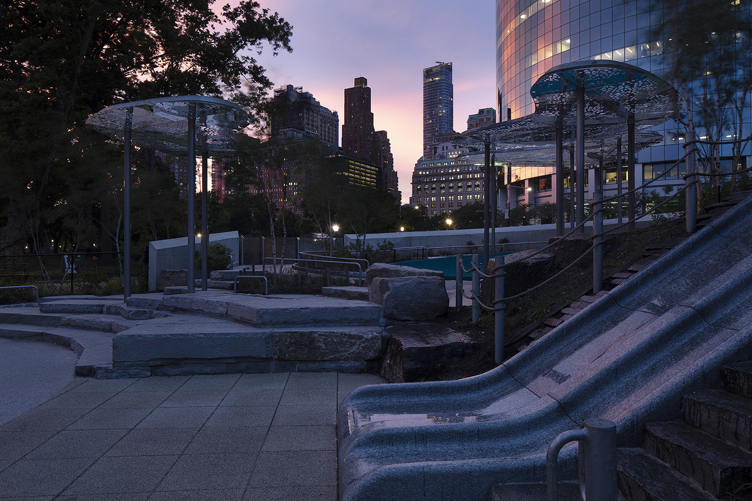 The Battery Playscape at twilight, showing the granite slides and custom cloud canopies