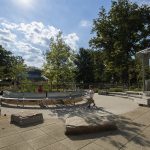 Two children walk by metal benches at the Battery Playscape