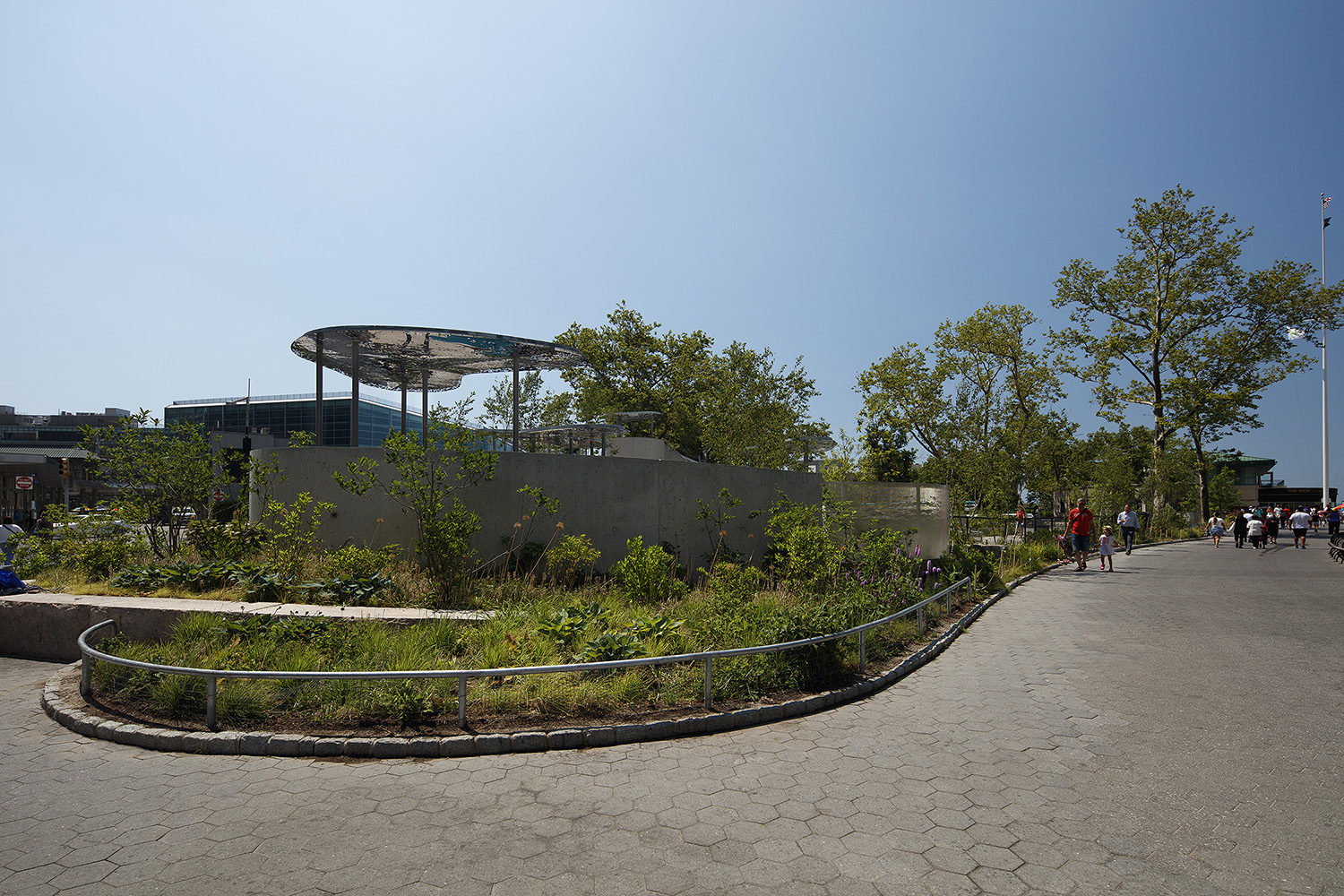 Battery-Playscape_shade-clouds_custom-panels_001 Paved pathway next to Battery Playscape with custom perforated metal shade structures in the background