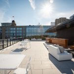 White Foro tables and chairs on the rooftop terrace of Stewart McKelvey. Office buildings are in the background.