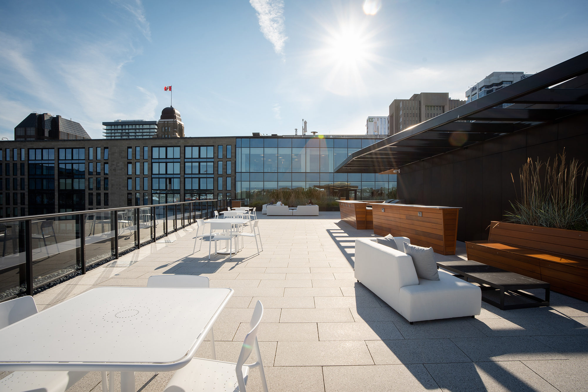 White Foro tables and chairs on the rooftop terrace of Stewart McKelvey. Office buildings are in the background.