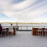 Two employees look out on the harbor from Foro stools on the Stewart McKelvey rooftop terrace