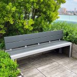 A Backed 1050 Bench is nestled between raised wooden planters on the roof deck of Viridian Apartments.