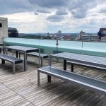Three sets of 1050 tables and benches are lined up on the roof deck of Viridian Apartments.