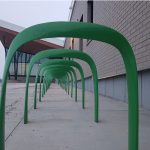 SC Bike Racks painted green are lined up in front of a building