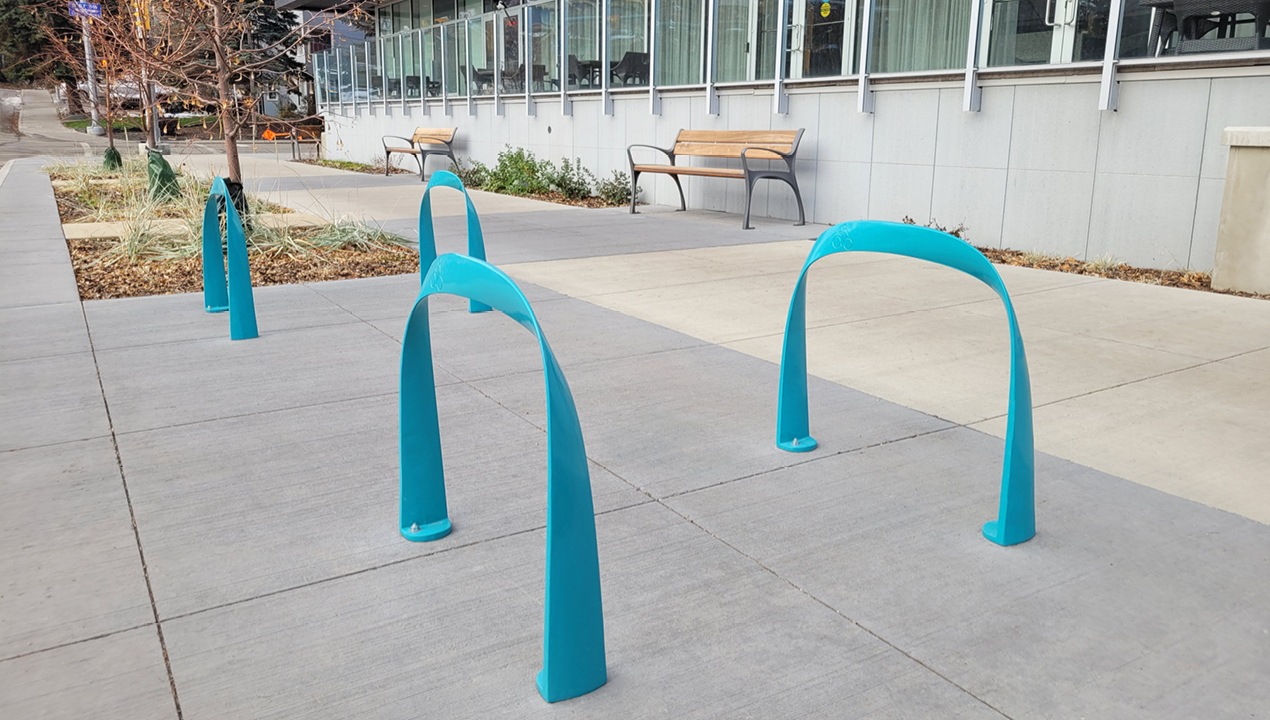 MBR-1600 SC Bike Racks, Surface Mount, Turquoise Gloss Powdercoat with retirement residence in background
