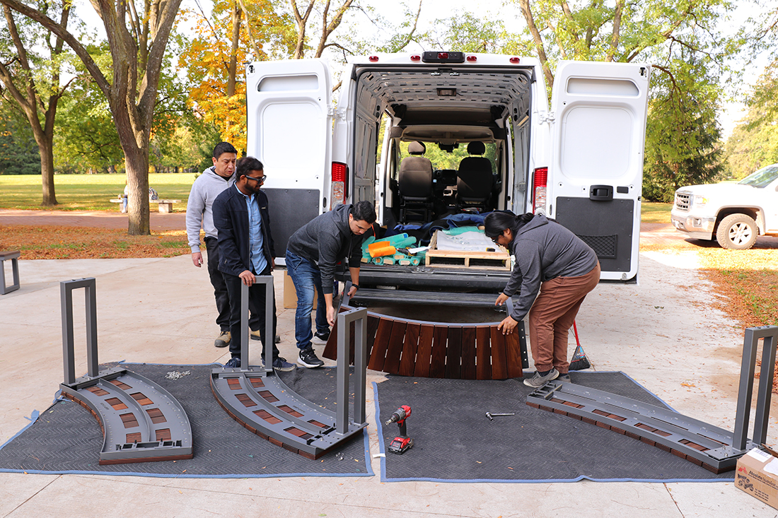 Four workers unload Maglin Ogden Benches from a van.