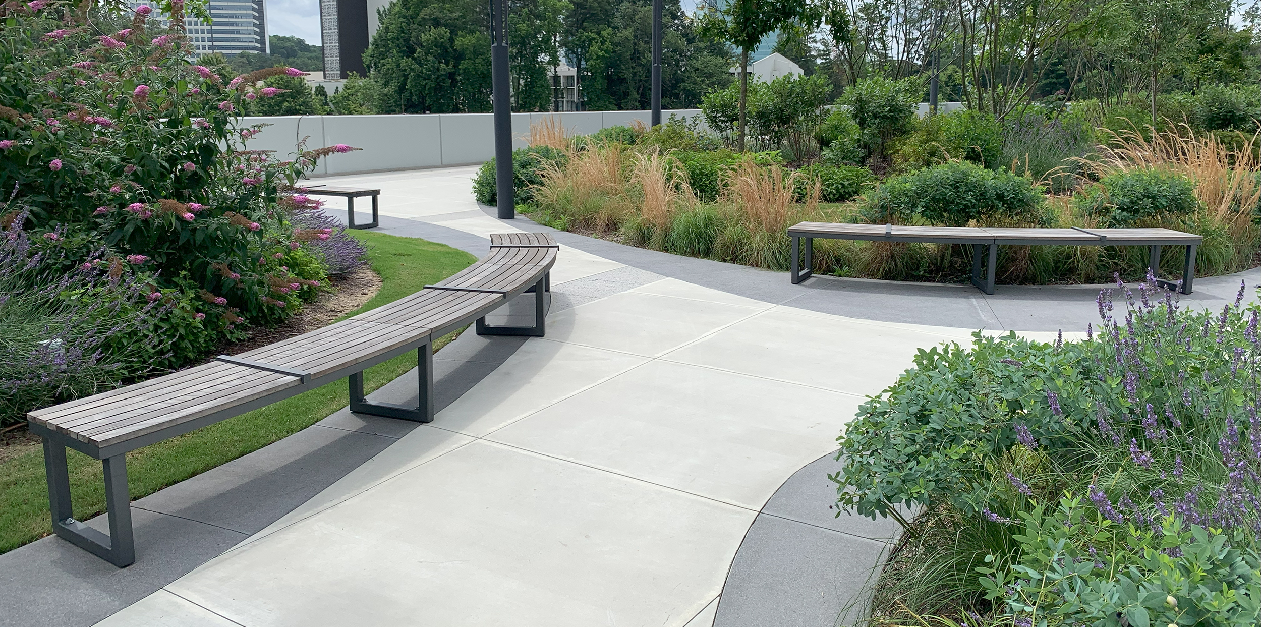 Backless Ogden Benches line pathway surrounded by greenery