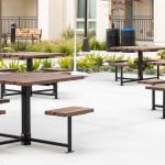 Maglin 400 Series cluster seating units are installed in an amenity courtyard at an apartment complex in Chula Vista, CA. A maglin Iconic Collection bench and waste and recycling containers are in the background as well as a bed of green plants.