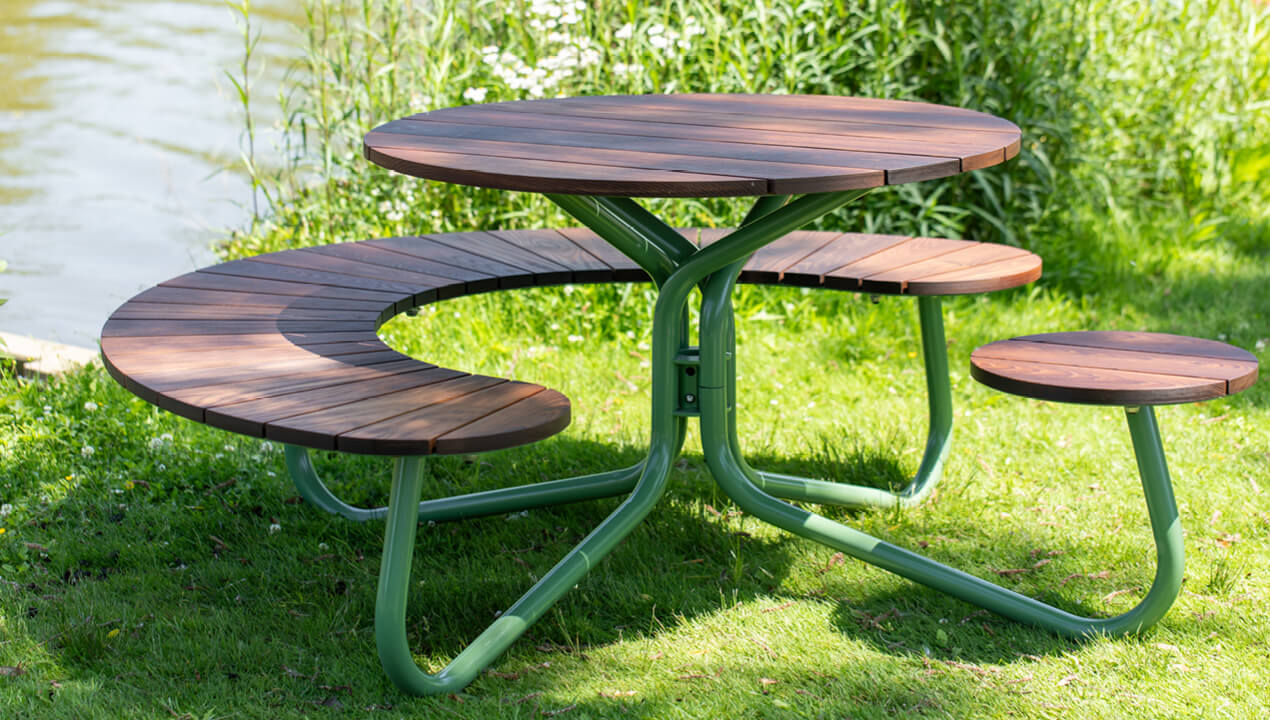 FAVA Cluster Seating in Thermally Modified Ash Wood with Reseda Green Powdercoat sitting on grass next to lake