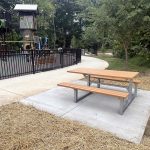 A newly installed Maglin 210 Cluster Seating picnic table with extended wheelchair accessible table top next to the playground at Rosedale Nature Park