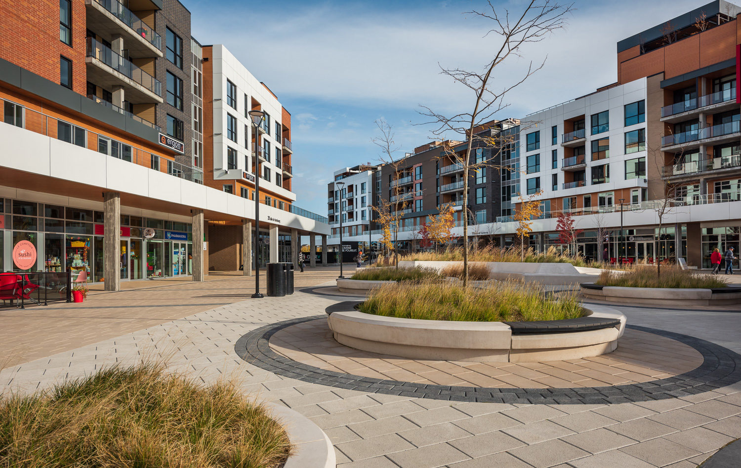 Several raised circular concrete planting beds offer seating with Ogden Benches wallmounted on top.