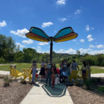 Butterfly shaped shade structure provides shade for family members enjoying the outdoors on Maglin's yellow 720 Chairs