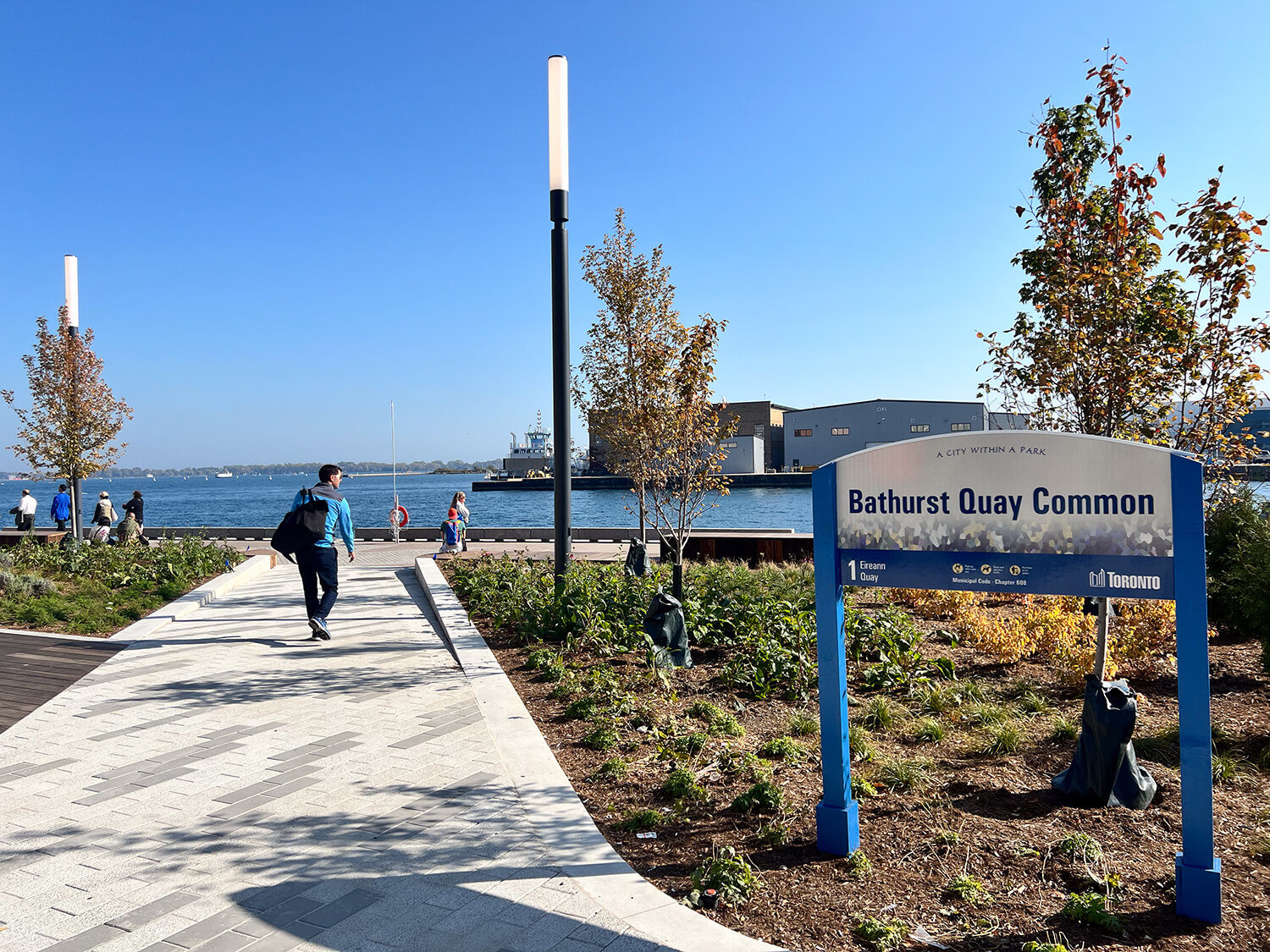 Bathurst Quay Common sign at entrance to the waterfront park with person walking towards the water