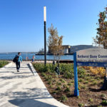 Bathurst Quay Common sign at entrance to the waterfront park with person walking towards the water